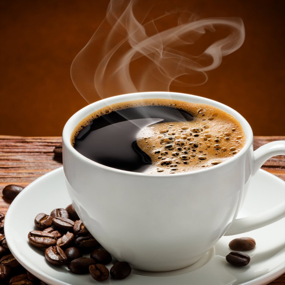 hot black coffee in a cup with coffee beans